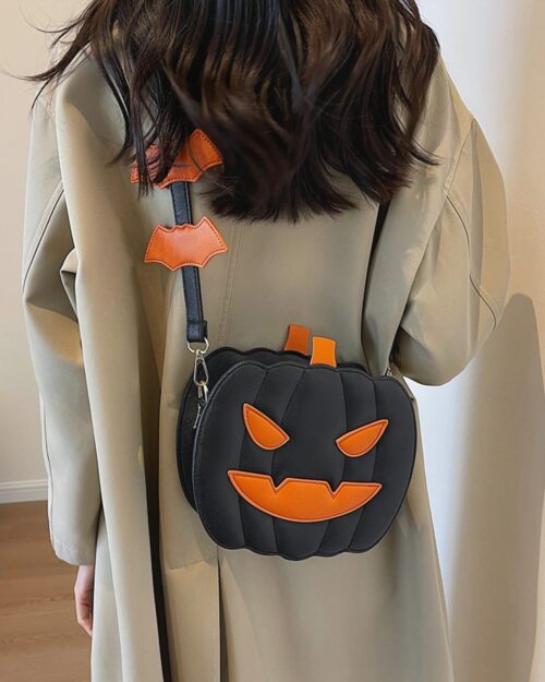 Black pumpkin halloween bag with orange accents, attached to a crossbody strap.