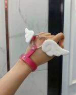 Close-up of Winged Love Bracelets - Harajuku Aesthetic on a wrist, featuring pink leather and white angel wings.