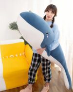 A blue and white kawaii whale plushie held by a person.