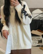 Close-up of a Korean aesthetic sweater with a cable knit design and bow detail.