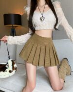 Brown vintage aesthetic mini skirt with pleats, worn by a model.