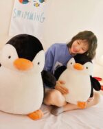 Two Pip the Chonky Penguin Plushies, one in a child's hands and another nearby.