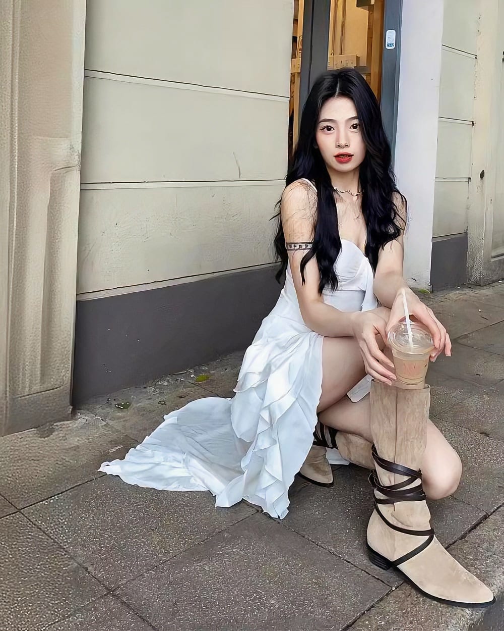 Woman wearing a white ruffled sling dress - Coquette aesthetic dress, casual street style with boots and iced coffee.