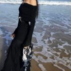 Black gothic aesthetic dress on a beach, featuring a dramatic, flowing silhouette and long sleeves.