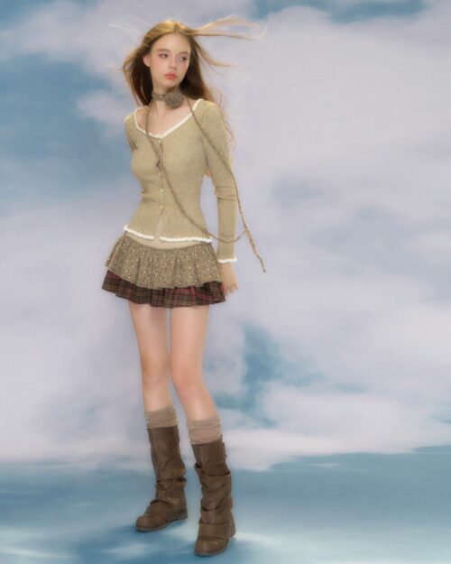 Model wearing a beige vintage aesthetic cardigan, plaid skirt, and boots.