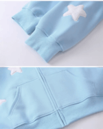 Close-up of a light blue harajuku hoodie with white star embroidery on the chest and sleeves.