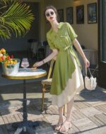 Woman wearing a green french vintage dress with a beige skirt, outdoors.