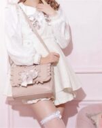 Pink vegan leather Jirai kei bag with ruffles and bow details, worn by a model.