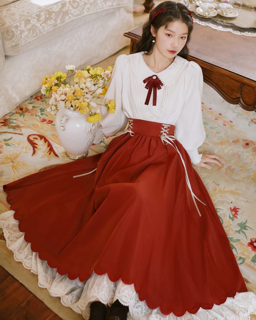 Woman wearing a cottagecore aesthetic dress with a red bow and gathered skirt.