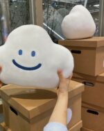 A Kawaii happy cloud plushie being held on a cardboard box.