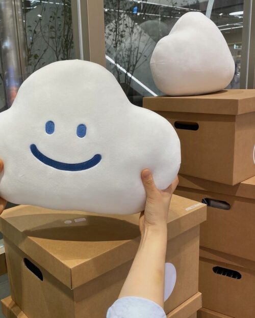 A Kawaii happy cloud plushie being held on a cardboard box.