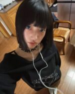 Close-up view of a grunge aesthetic sweater, dark pullover with off-shoulder design.