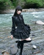 Black laced gothic lolita dress worn by a model near a river.