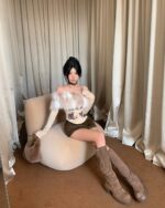 Model wearing a fluffy y2k aesthetic top with printed graphics, paired with boots.