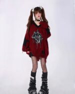 Woman wearing a red loose gothic sweater with black accents and a spider web graphic.