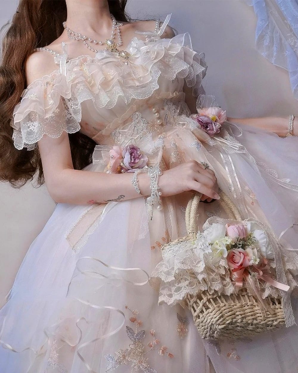 Close-up of a floral lolita dress featuring ruffles and lace details, with a basket and flowers.
