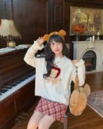 Model wearing a white cottagecore bear sweater with apple and bear details, featuring attached bear ears.