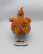 Orange fat chicken plushie on a scale, soft and fluffy toy.