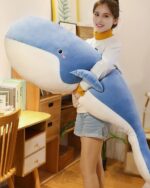 A blue kawaii whale plushie held by a person, showcasing its size and texture.