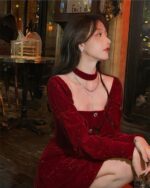 Woman wearing a red festive velvet dress, featuring a high neckline and puffed sleeves.