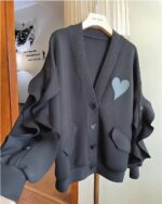Black lace cardigan kawaii hanging on a hanger, featuring heart detail.
