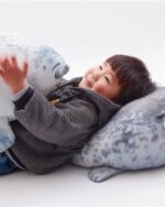 Child holding Yuki the seal plush, a soft, gray plush toy.