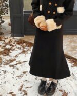 Close-up of a french aesthetic outfit featuring a black coat with faux fur cuffs and black shoes.