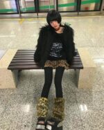 Off shoulder dark pullover sweater featuring a grunge aesthetic, worn by a person in a public transit setting.