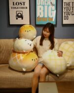 Several Kawaii Melonwan plushies, featuring yellow and white patterned designs, are displayed on a sofa.