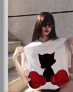 A woman wearing an astro silhouette t-shirt with a black cat design, paired with red shoes.