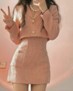 Pink retro aesthetic suit with a blazer and skirt, featuring pearl necklace and a peace sign.