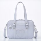 Light pink japanese schoolbag with handles and detachable strap.