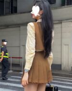 Woman wearing a korean school uniform style three-piece suit, beige color.