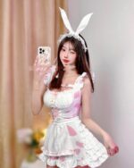 Woman wearing a bunny girl maid costume with a pink and white dress and ears.