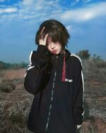 A person wearing a black japanese sporty jacket with white stripes outdoors.