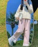 Woman wearing pink kawaii laced pants with lace trim, holding a plush toy outdoors.