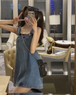 Woman wearing a blue kawaii denim dress with chain straps.