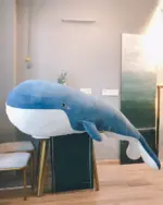 Blue kawaii whale plushie, Bubbles, resting on a wooden chair.