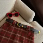 Plaid mini skirt featuring a preppy aesthetic, styled with sunglasses and a belt.