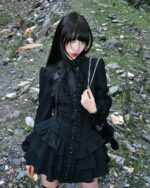 Black laced gothic lolita dress featuring ruffled sleeves and layers, worn by a model outdoors.