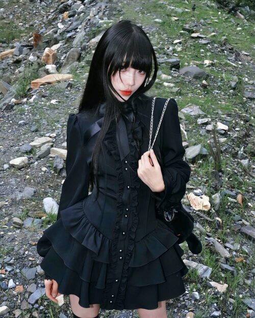 Black laced gothic lolita dress featuring ruffled sleeves and layers, worn by a model outdoors.