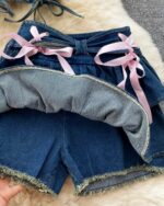 Two-piece coquette denim set featuring a ruffled top and denim shorts with lace ties.