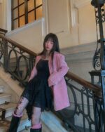 Model wearing a gothic aesthetic dress with lace and fishnet stockings, styled with a pink jacket.