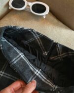 Close-up of a plaid mini skirt with a preppy aesthetic, featuring a zipper detail.