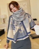 Woman wearing a gray vegan cashmere scarf with a floral pattern.