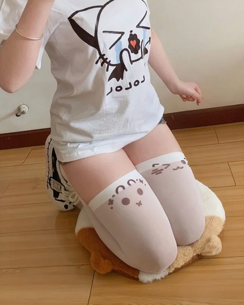 White kaomoji cute stockings with cat and face design on a wooden floor.