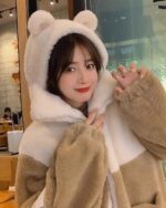 Woman wearing a brown bear ear jacket with a hood and fluffy ears.