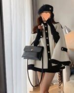 Woman wearing a french style cape coat, beret, and gloves, with a handbag.