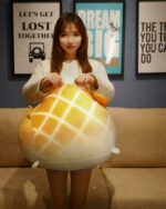 A large, yellow Kawaii melonwan plushie being held by a person.