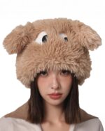 A fluffy eyed hat worn by a woman, featuring plush ears and large eyes.